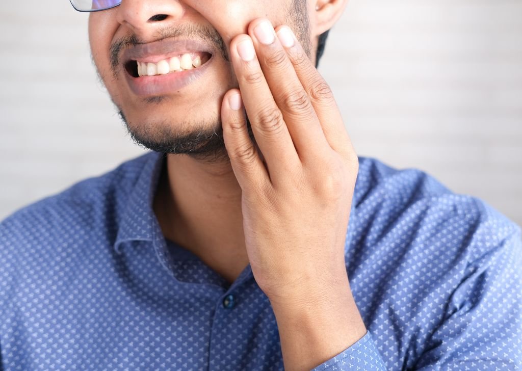 Young man experiencing pain in his teeth. Likely a dental filling that needs replacing soon.
