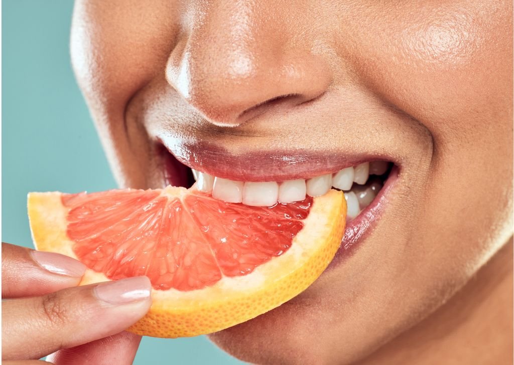 Healthy gums and teeth biting into juicy grapefruit segment.