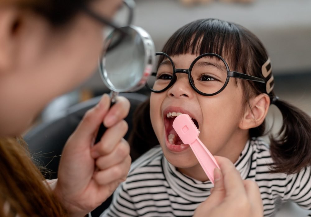 Cute Asian child playing with doctor dentist toy set, child shows how to clean and care for teeth.