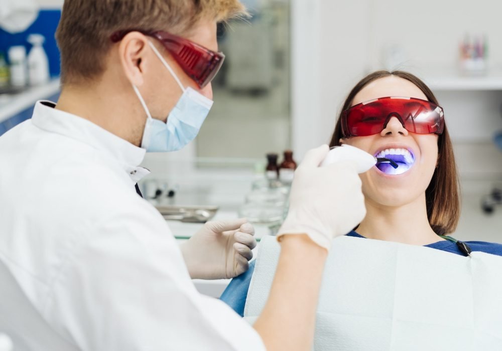 Whitening teeth procedure during visit at dentist.